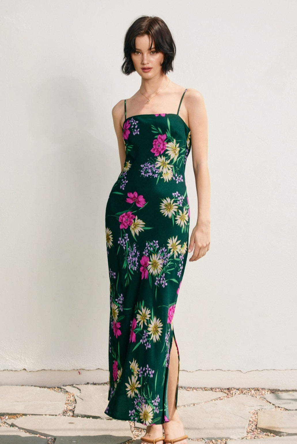 Woman wearing a green floral dress against a plain background