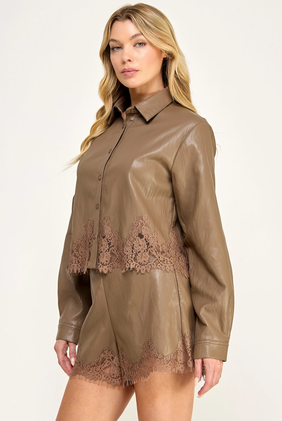 Clara Lace Trim Button-Down Top featuring a smooth faux leather finish, classic collar, long sleeves with buttoned cuffs, and delicate lace trim along the hem. Designed with a slightly cropped silhouette and a flattering, feminine fit. Pairs perfectly with the matching Clara Lace Trim Shorts for a chic, coordinated look.