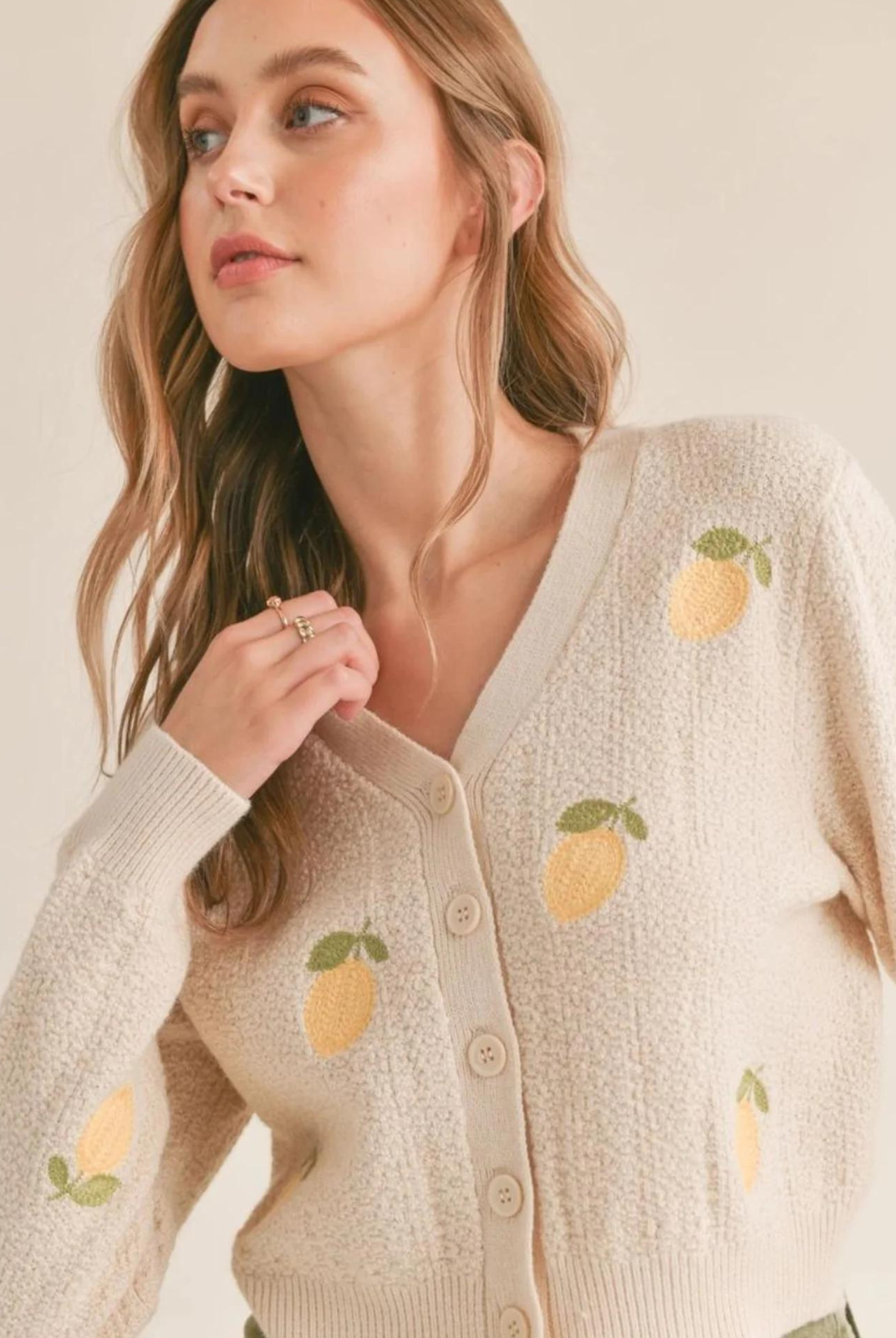 Sadie and Sage Esme Lemon Cardigan. Elevate your wardrobe with the Esme Lemon Cardigan! This cream button front cardigan features delicate embroidered lemon details on the front, creating a fresh and playful look. Perfect for adding a touch of whimsy to any outfit. Style #AG1417