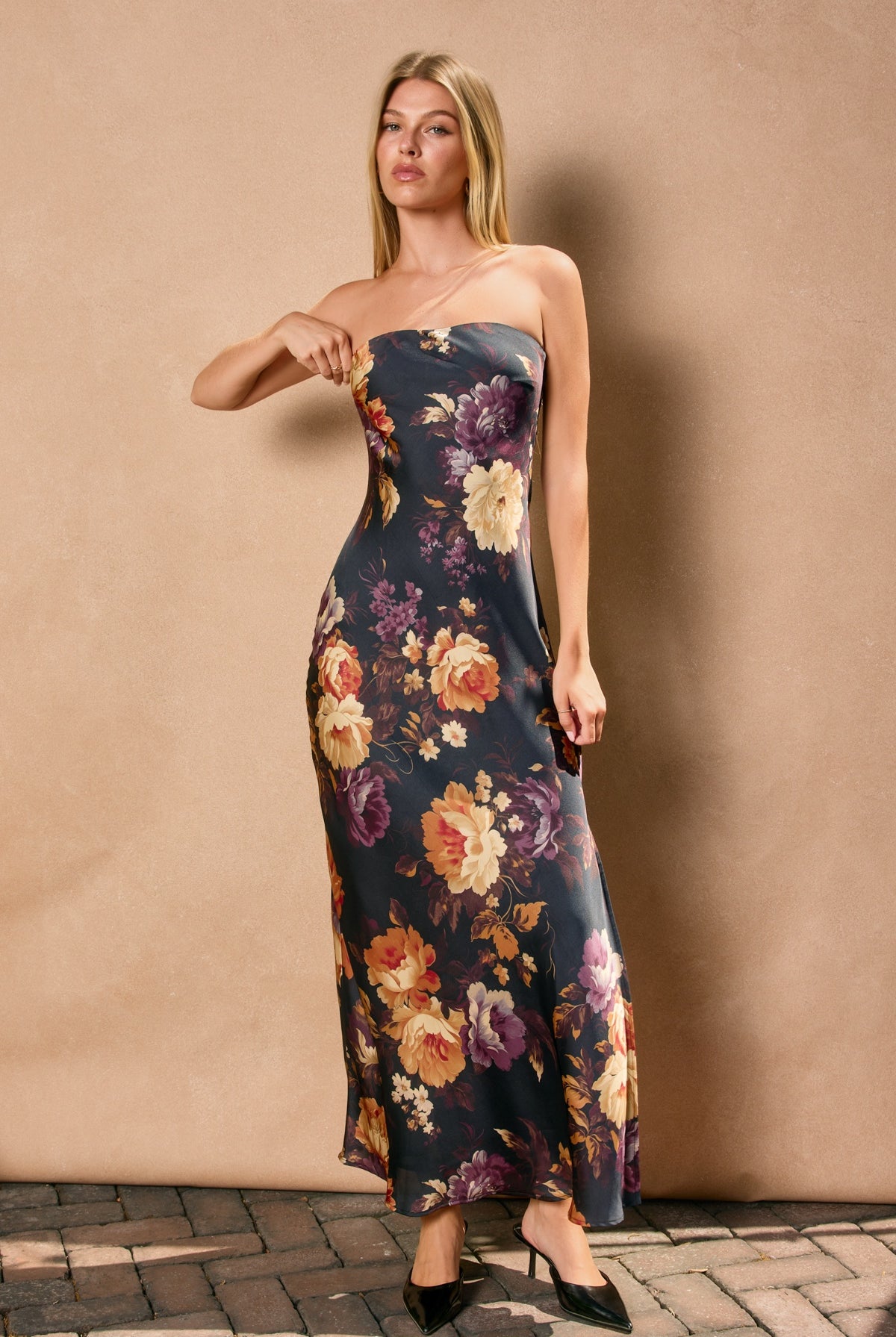 Woman wearing a strapless floral dress against a beige wall.
