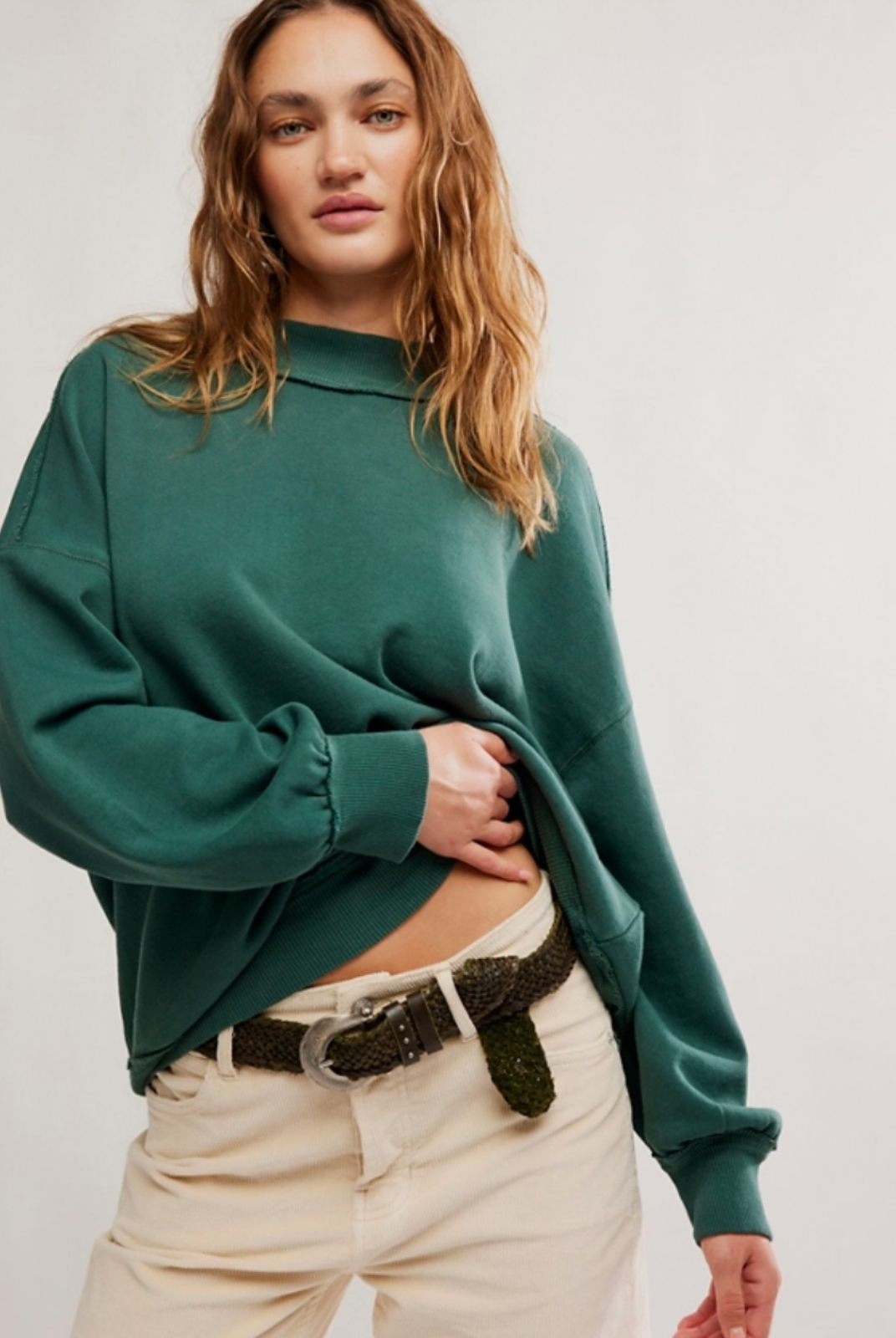 A girl wearing an oversized turtleneck with beige pants