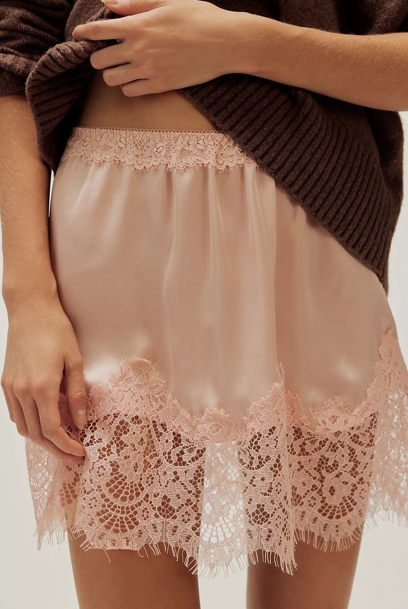 woman wearing a peach coloured satin mini skirt with a lace hem