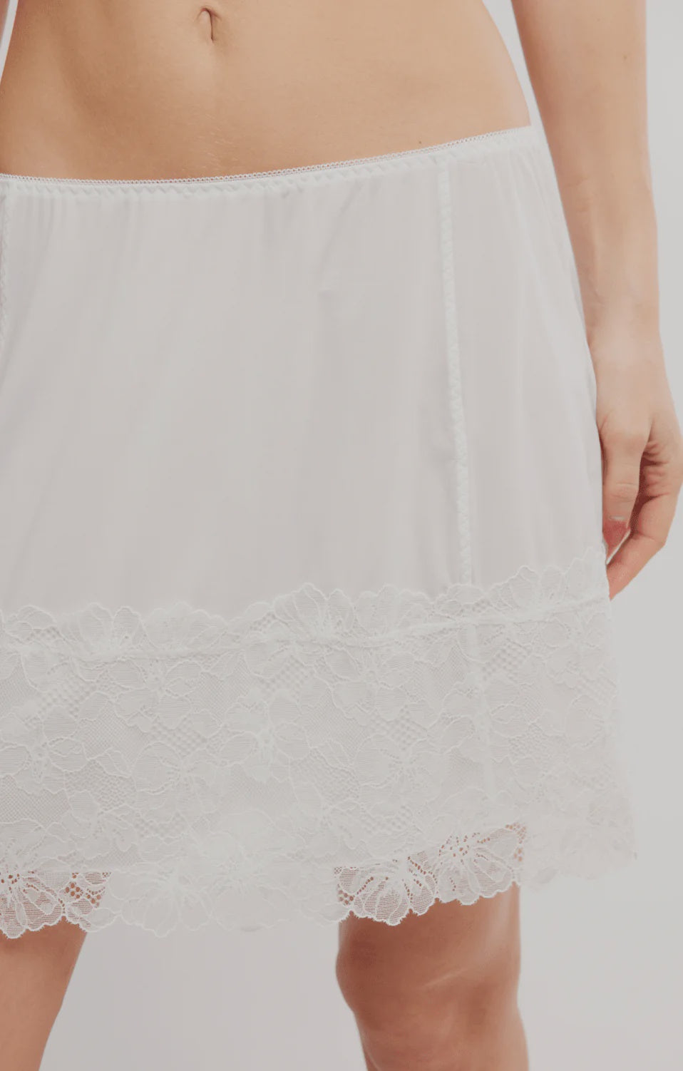 White lace-trimmed skirt worn by a person on a plain background