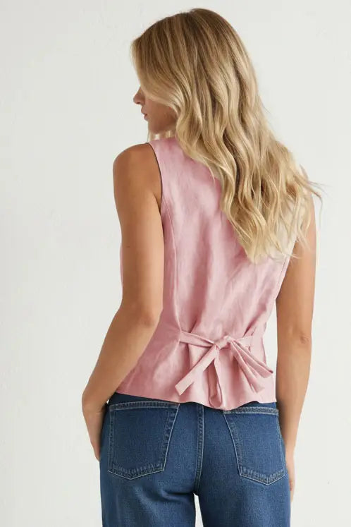 Light pink sleeveless woven vest featuring a round neckline, button-front closure, curved hem, and a tailored fit. Designed with an adjustable tie-back detail for a flattering, customizable silhouette.