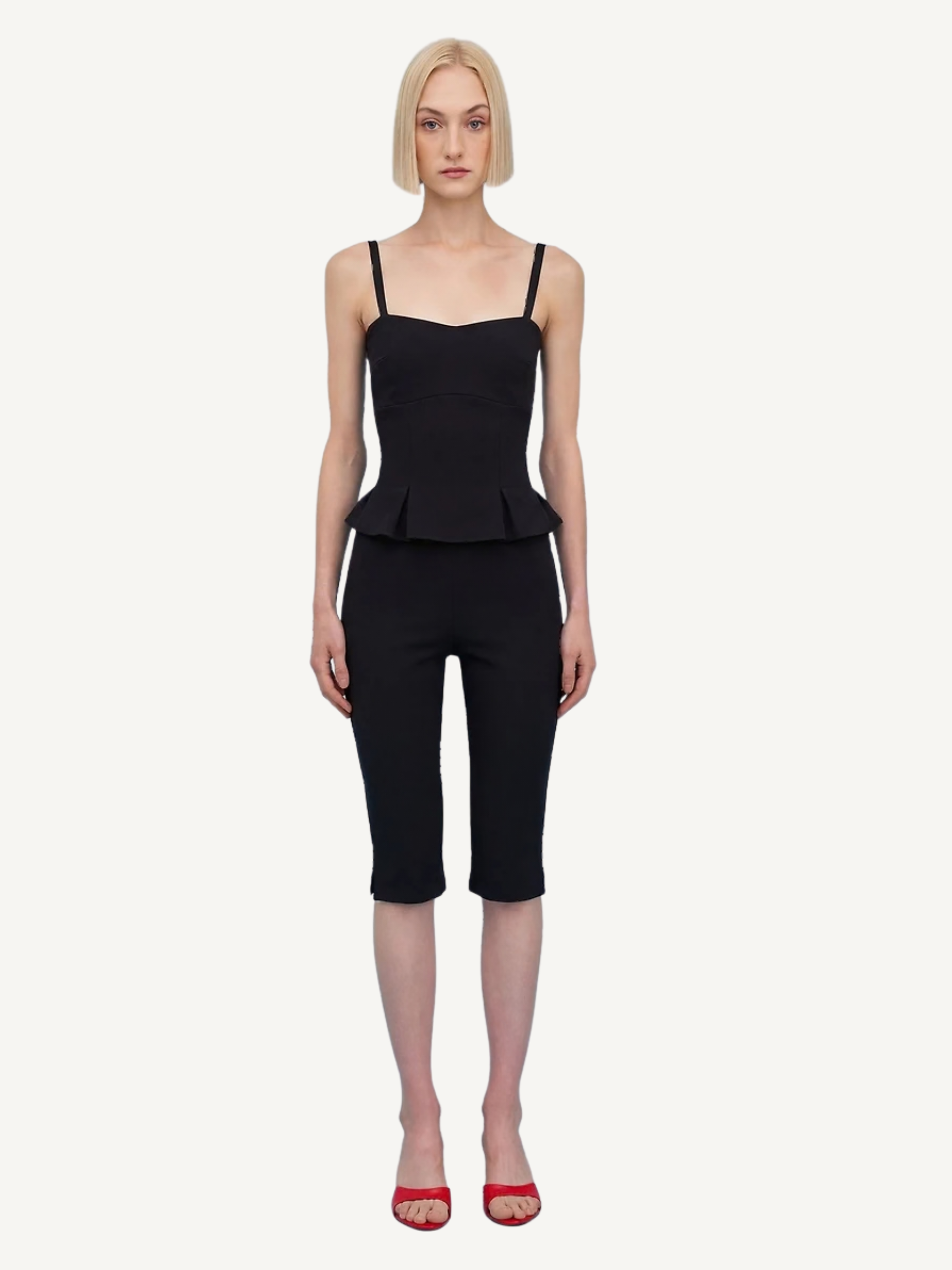 Woman wearing a black peplum top and capri pants on a white background