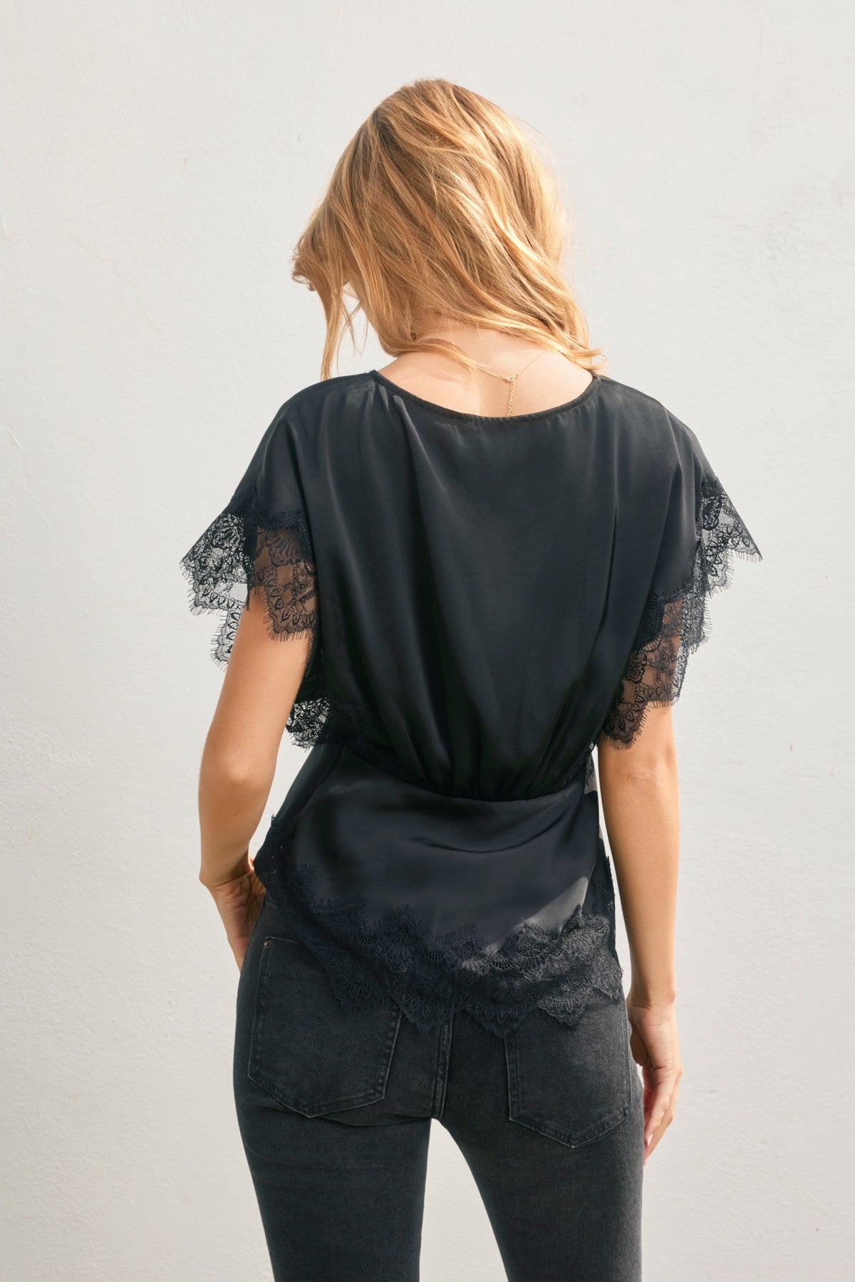 Black top with lace sleeves worn by a person on a plain background