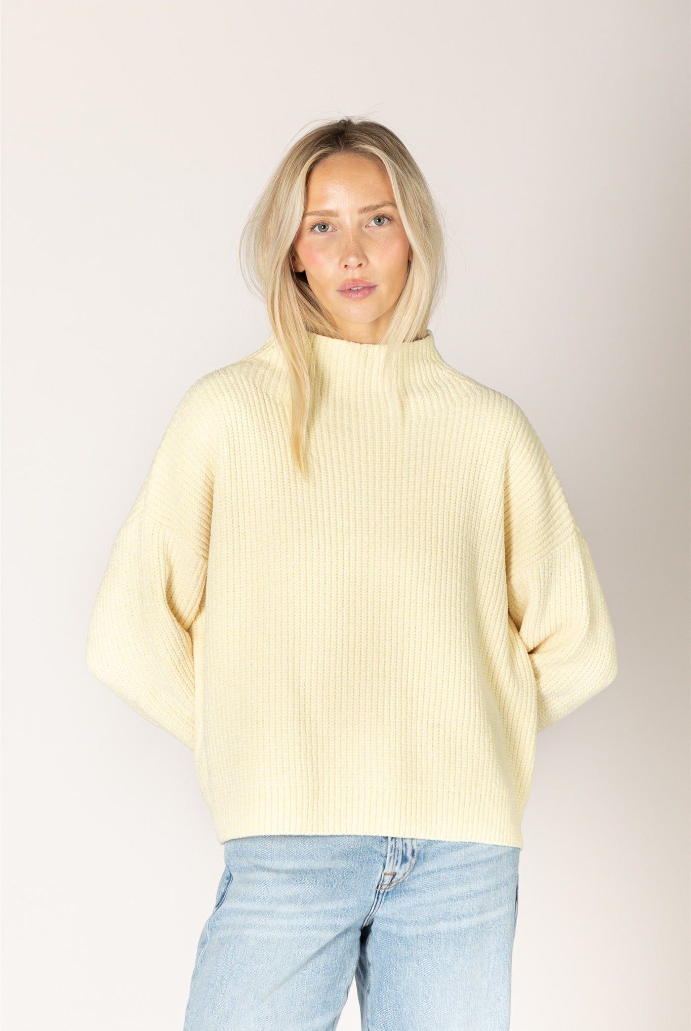 pale yellow ribbed knit sweater featuring a mock neckline, relaxed fit, and long sleeves.