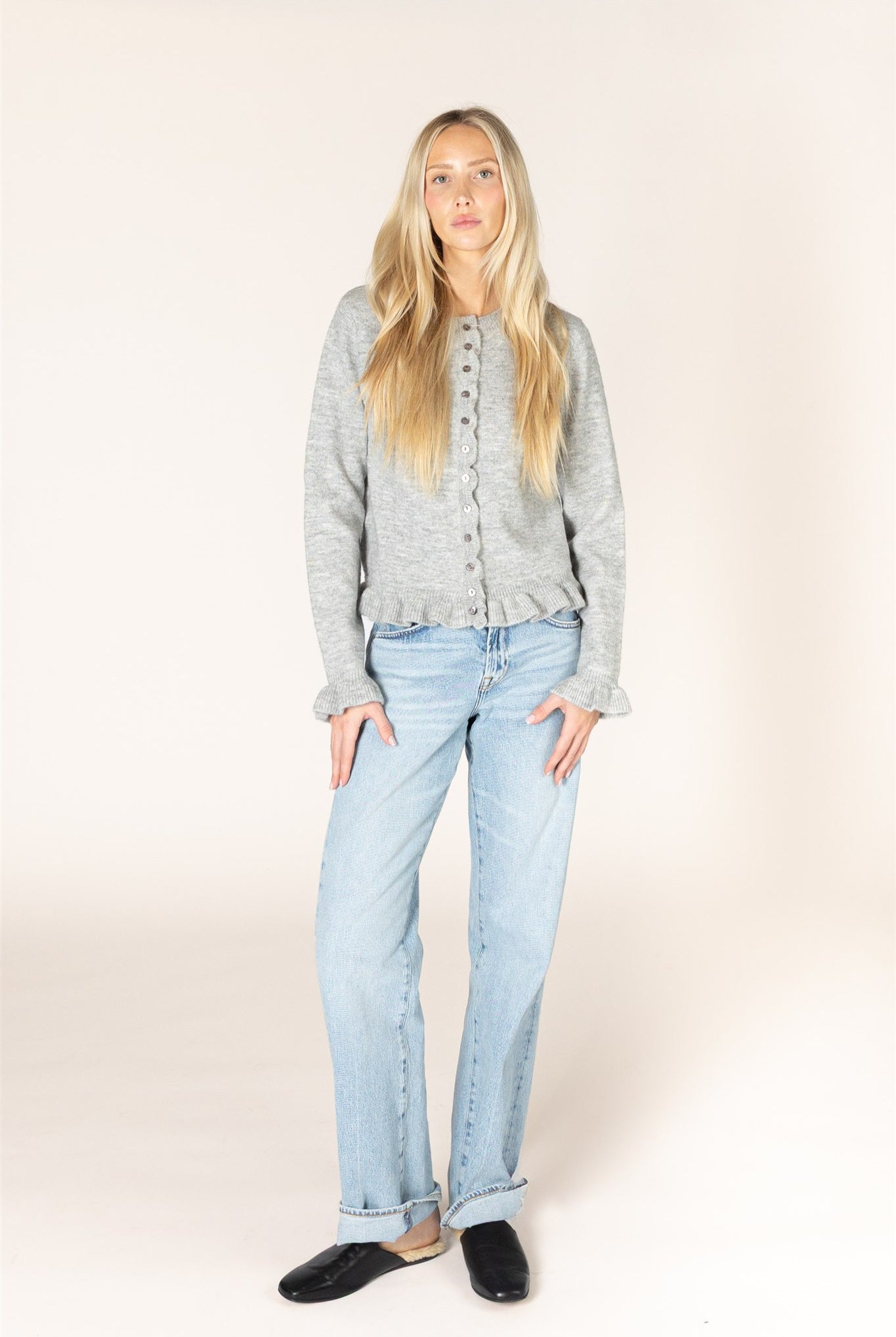Sterling grey knit cardigan with a crew neckline and button-front closure, featuring delicate ruffle trim along the placket, hem, and cuffs.