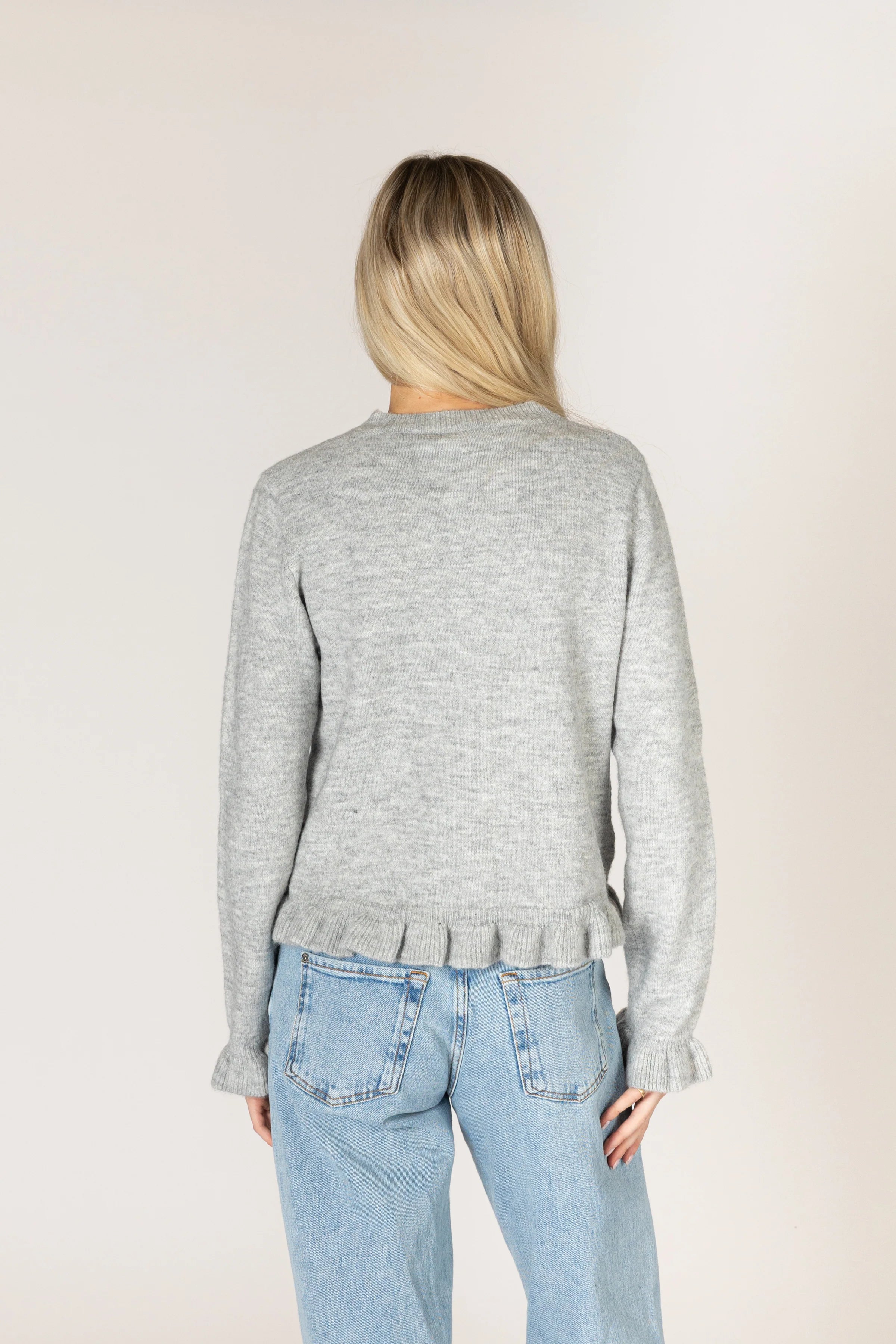 Sterling grey knit cardigan with a crew neckline and button-front closure, featuring delicate ruffle trim along the placket, hem, and cuffs.