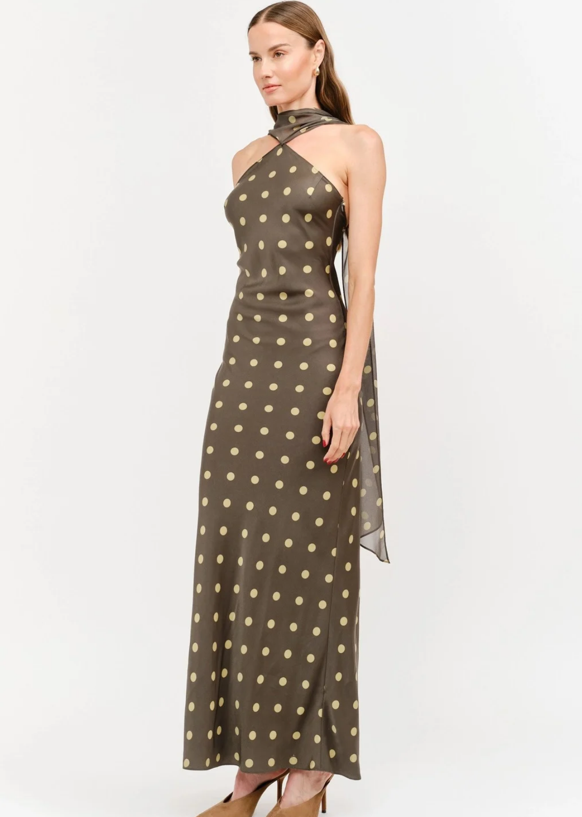 Make an unforgettable entrance in this stunning halter-neck midi dress. Showcasing a chic, classic polka dot motif against a rich, dark background, this piece features a sophisticated high neckline with a twisted halter strap detail that frames the shoulders to perfection. Cut in a sleek, fluid silhouette that gracefully skims the body, it offers an effortless blend of retro charm and contemporary style. 