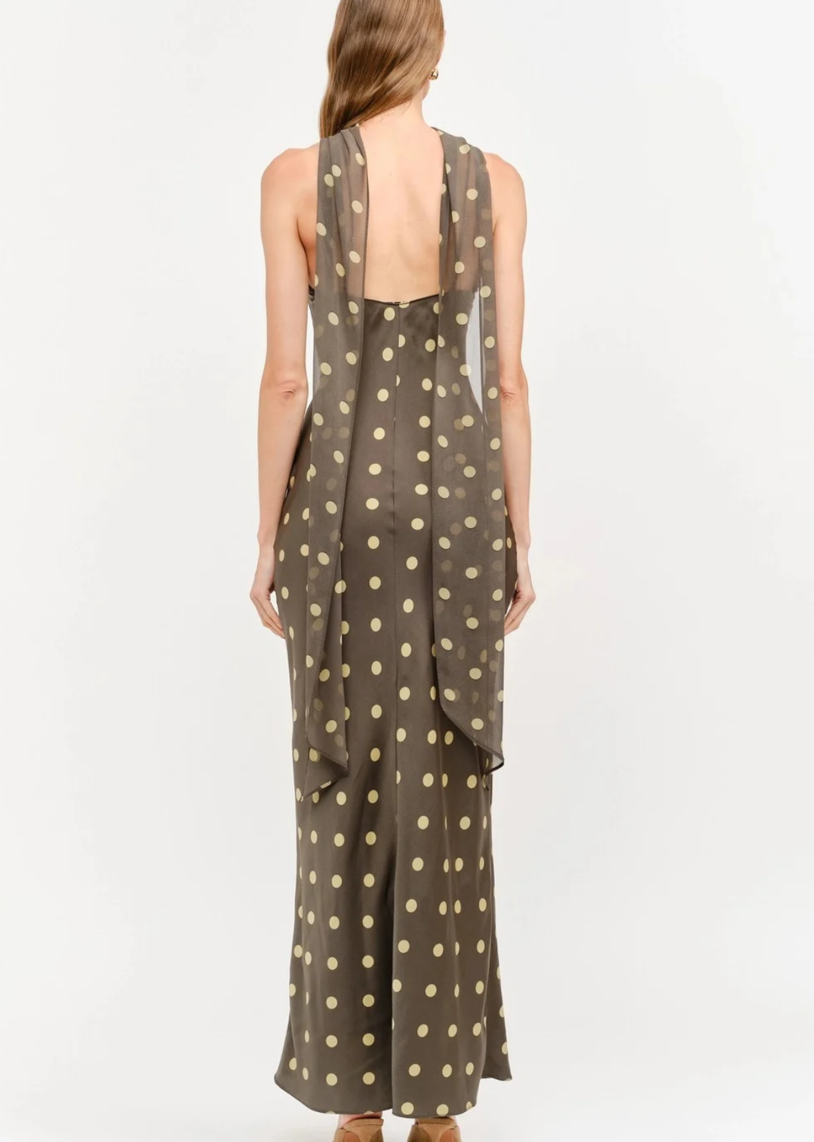 Make an unforgettable entrance in this stunning halter-neck midi dress. Showcasing a chic, classic polka dot motif against a rich, dark background, this piece features a sophisticated high neckline with a twisted halter strap detail that frames the shoulders to perfection. Cut in a sleek, fluid silhouette that gracefully skims the body, it offers an effortless blend of retro charm and contemporary style. 