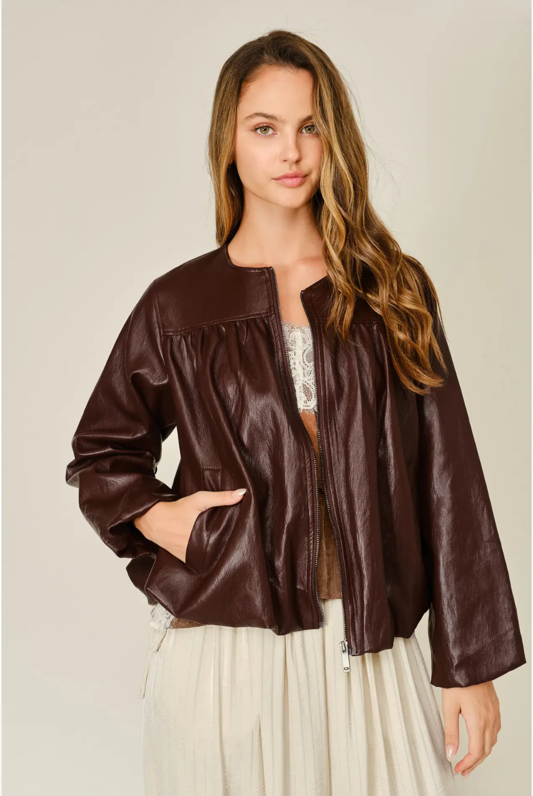 Merlot relaxed balloon bomber jacket in mahogany vegan leather, featuring a round neckline, front zip closure, pleated detailing, and elasticized cuffs and hem.