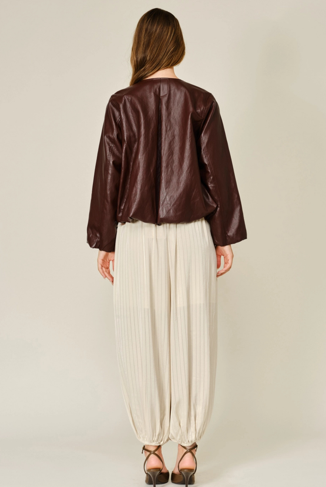 Merlot relaxed balloon bomber jacket in mahogany vegan leather, featuring a round neckline, front zip closure, pleated detailing, and elasticized cuffs and hem.