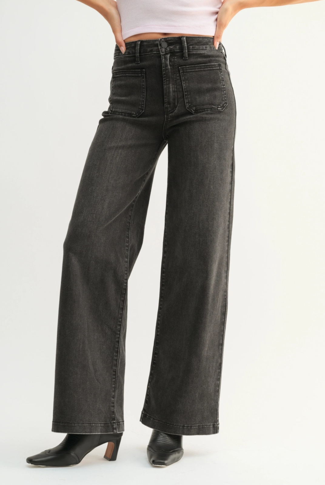 Person wearing black wide-leg jeans on a white background