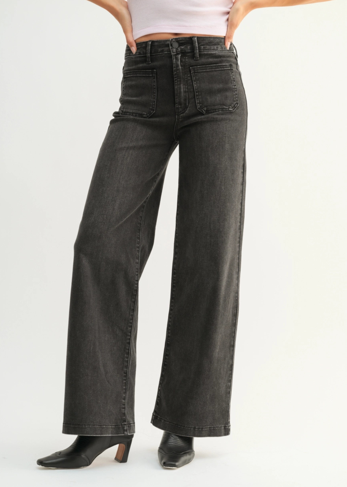 Person wearing black wide-leg jeans on a white background