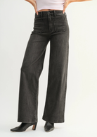 Person wearing black wide-leg jeans on a white background