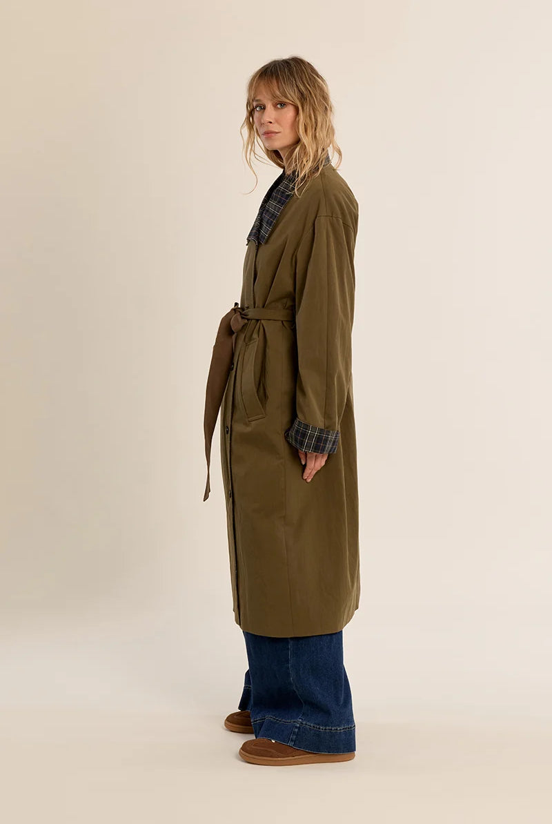 Long belted trench coat featuring a classic plaid lining, wide waist belt, front button closure, and side patch pockets.