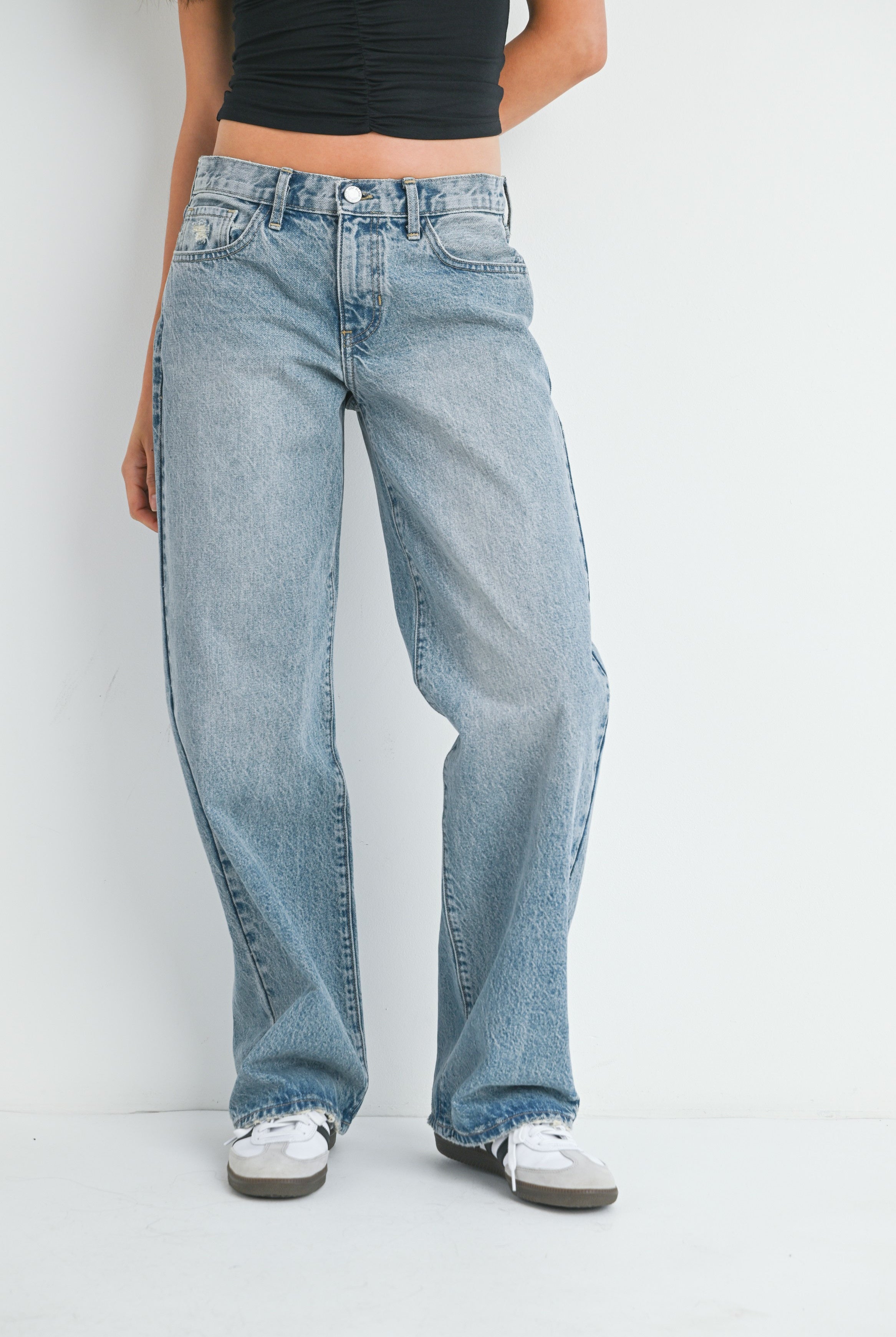 Person wearing light blue jeans and black top on a white background