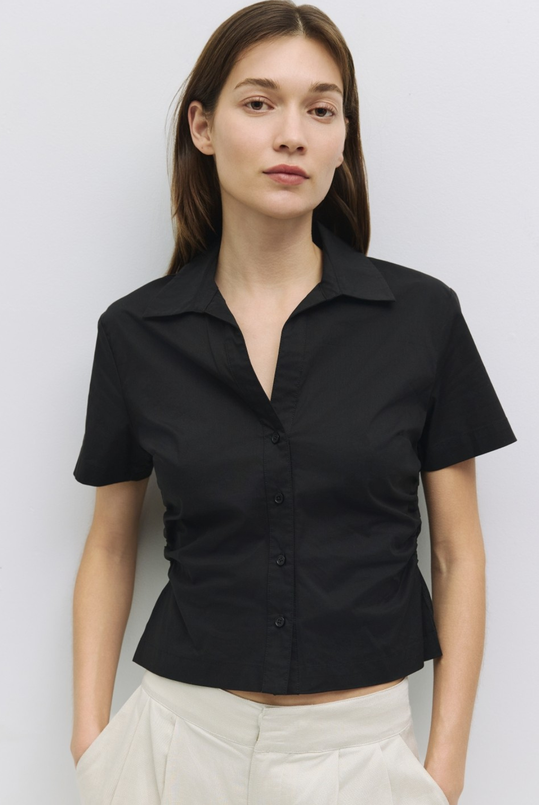 Woman wearing a black short-sleeve shirt against a white background