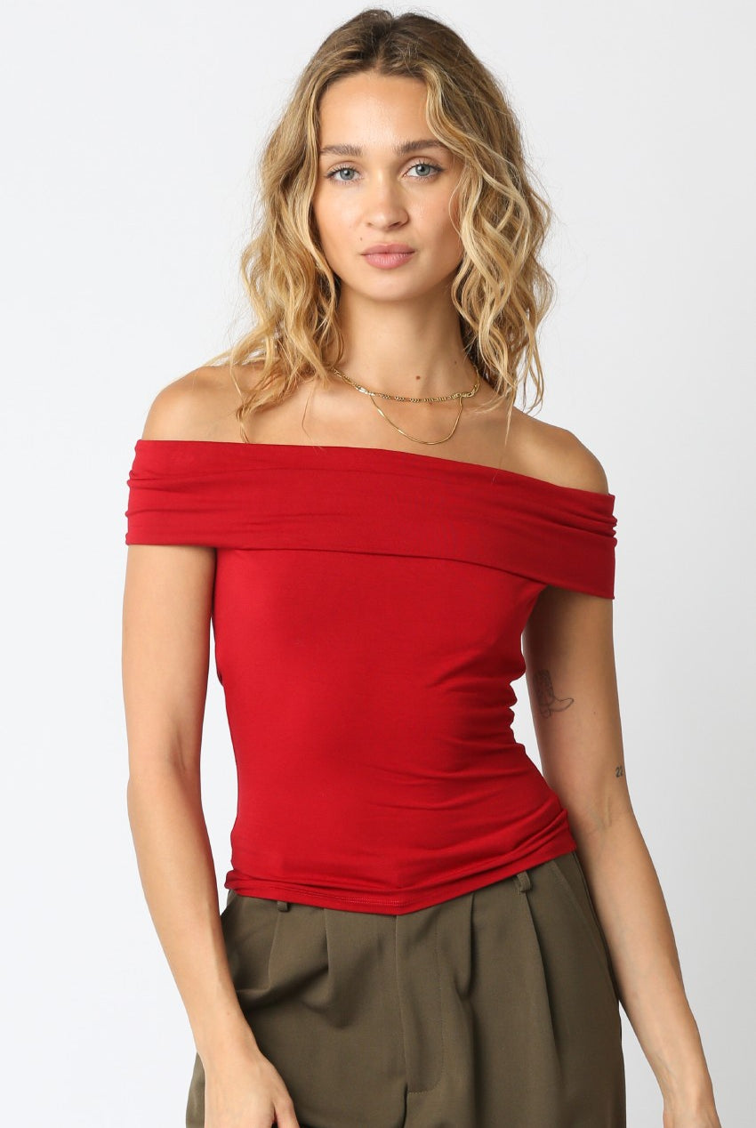 Woman wearing a red off-shoulder top against a white background