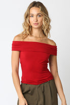 Woman wearing a red off-shoulder top against a white background