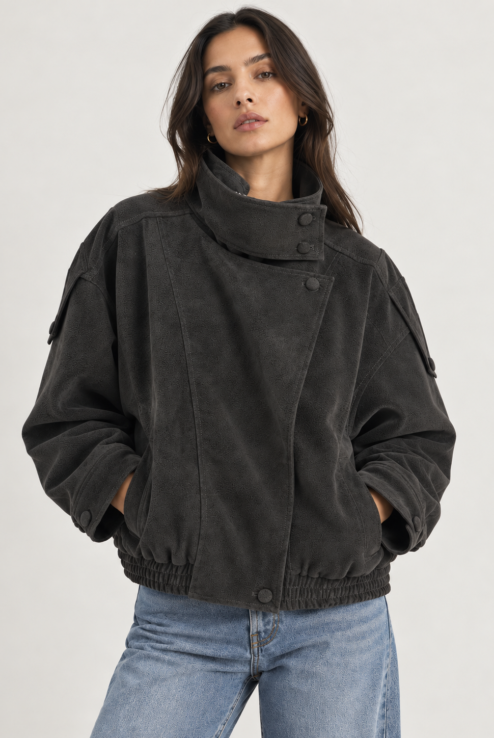 Model wearing the Tribeca Leather Bomber Jacket in black, featuring an oversized fit, high collar, asymmetrical front closure, tonal buttons, sleeve tab details, side pockets, and an elasticized hem.