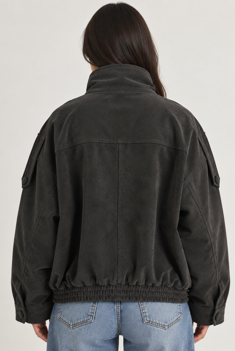 Model wearing the Tribeca Leather Bomber Jacket in black, featuring an oversized fit, high collar, asymmetrical front closure, tonal buttons, sleeve tab details, side pockets, and an elasticized hem.