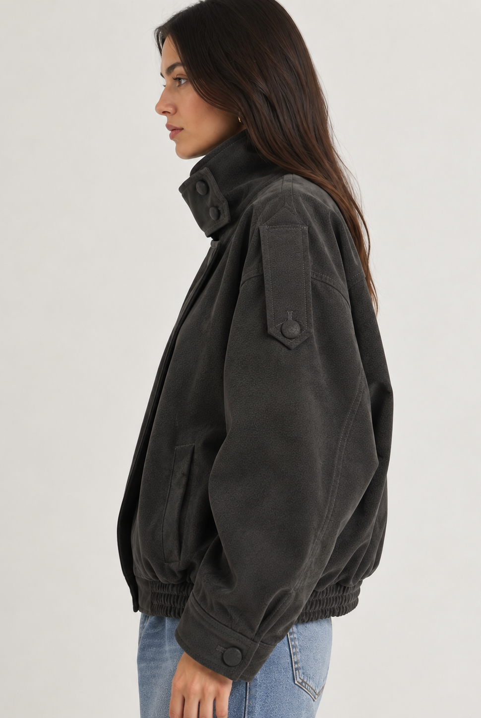Model wearing the Tribeca Leather Bomber Jacket in black, featuring an oversized fit, high collar, asymmetrical front closure, tonal buttons, sleeve tab details, side pockets, and an elasticized hem.