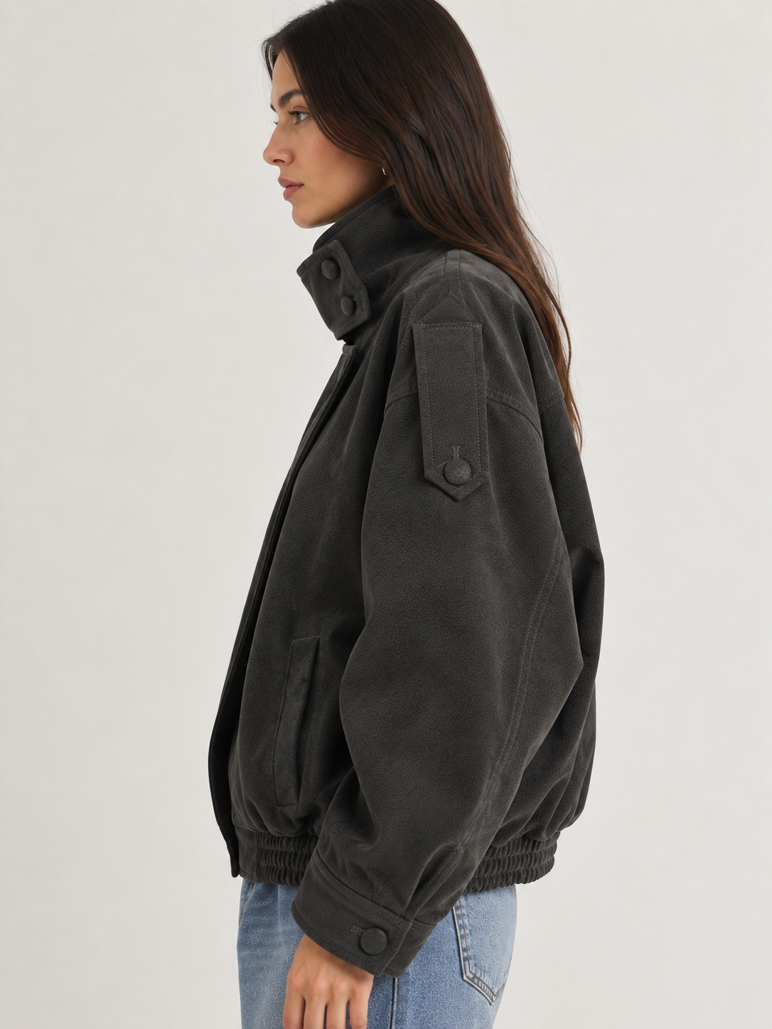 Model wearing the Tribeca Leather Bomber Jacket in black, featuring an oversized fit, high collar, asymmetrical front closure, tonal buttons, sleeve tab details, side pockets, and an elasticized hem.