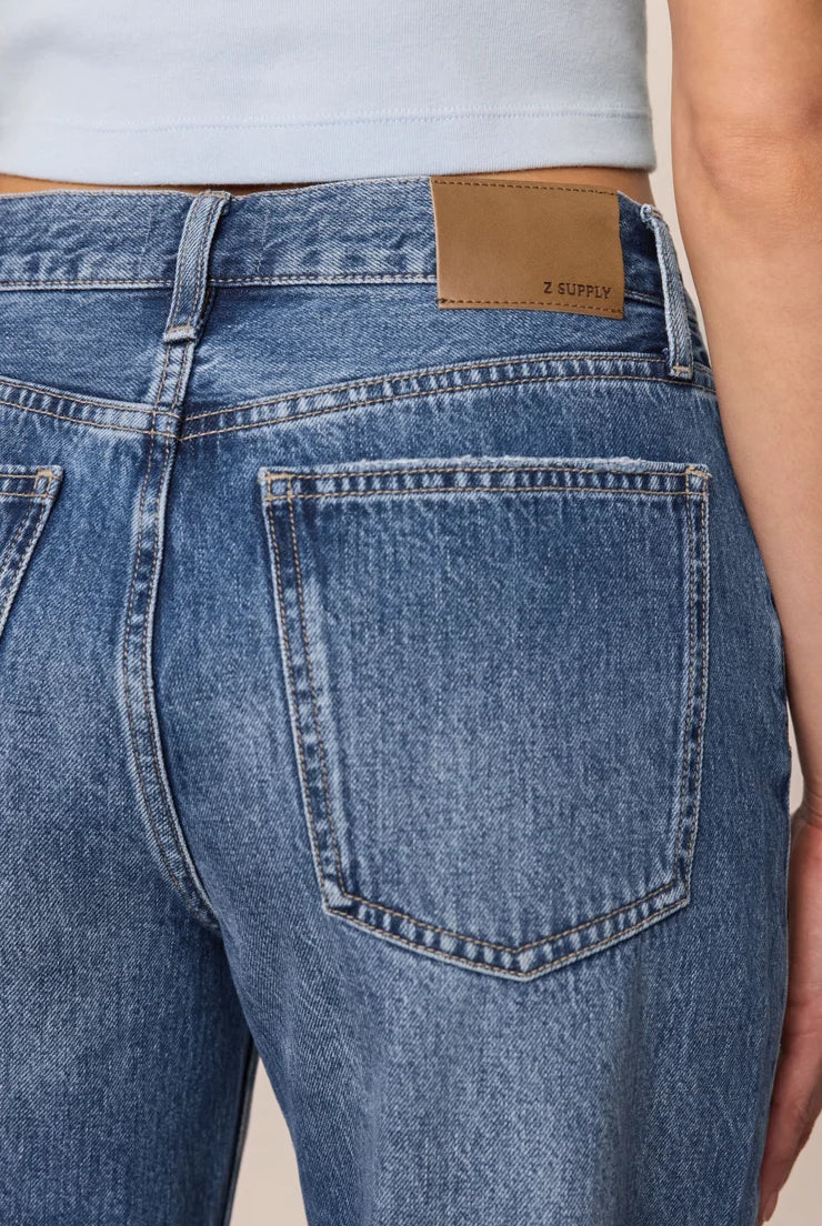 Vintage-wash blue mid-rise jeans featuring a relaxed bowed-leg silhouette, ankle-length hem, and classic five-pocket styling.