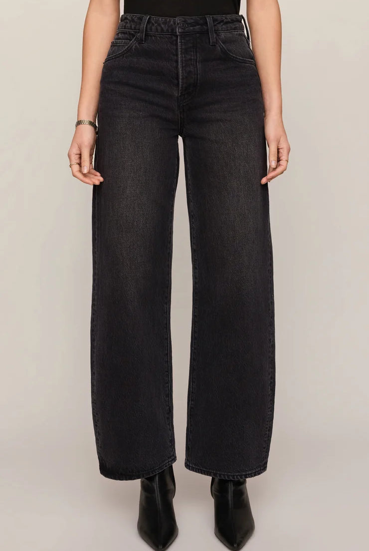 High-rise washed black jeans featuring a relaxed bowed-leg silhouette, full-length hem, and contrast whipstitch detailing inside the cuff.