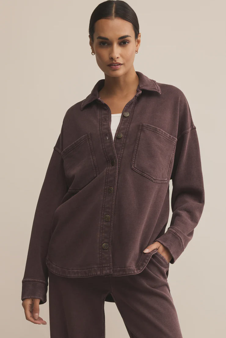 Woman wearing a brown shirt and pants against a beige background