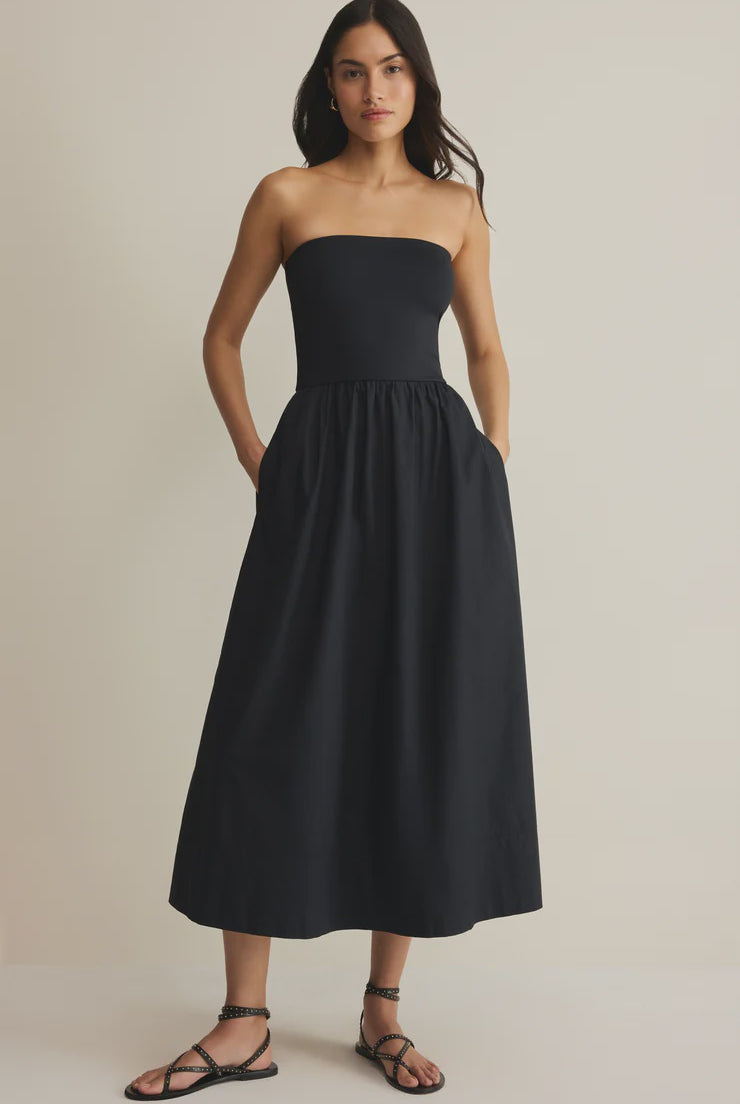 Woman wearing a black strapless dress against a plain background