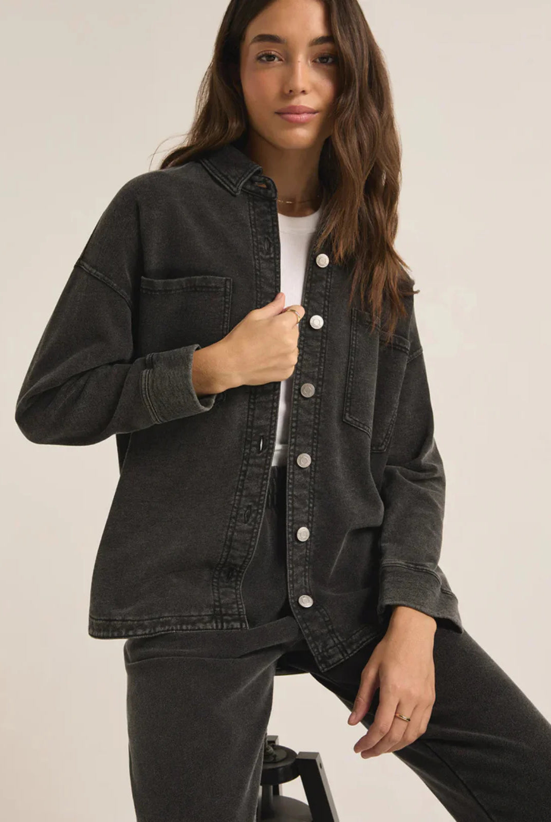 Woman wearing a black denim jacket on a plain background