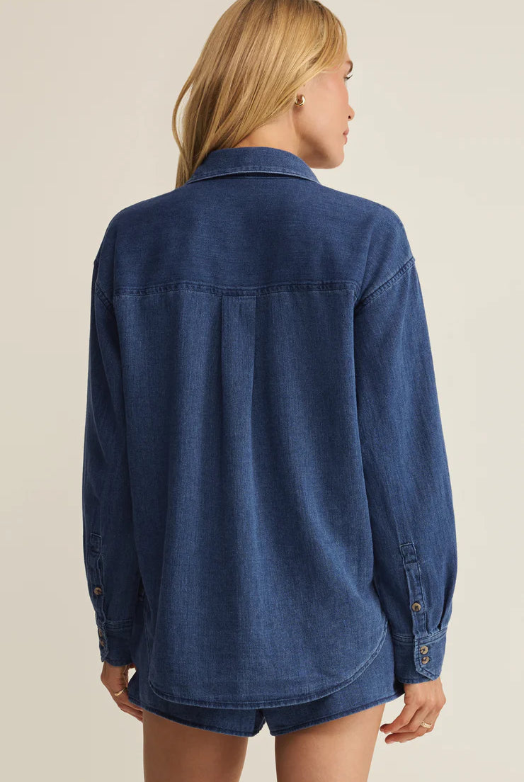 Person wearing a blue denim shirt on a beige background