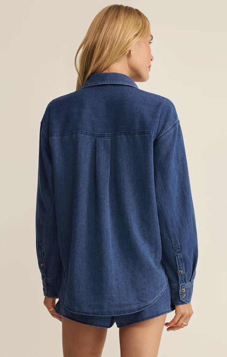 Person wearing a blue denim shirt on a beige background