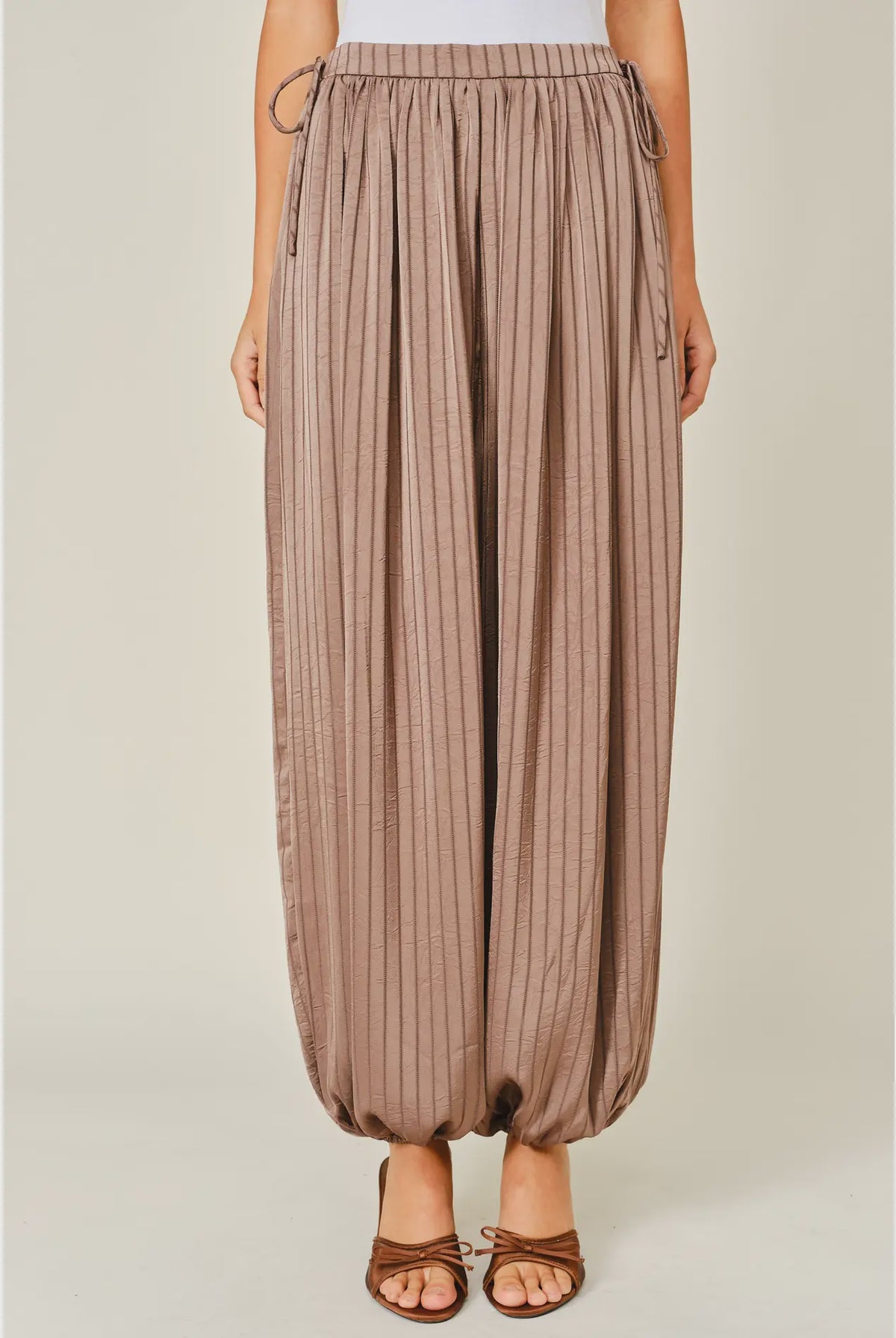 Zola Striped Satin Bubble Pants featuring a soft, glossy satin finish with a striped pattern, comfortable elastic waistband, adjustable drawstring side details, and functional side pockets. Designed with a relaxed, voluminous balloon silhouette and a flowy, lightweight feel for an effortlessly chic look.