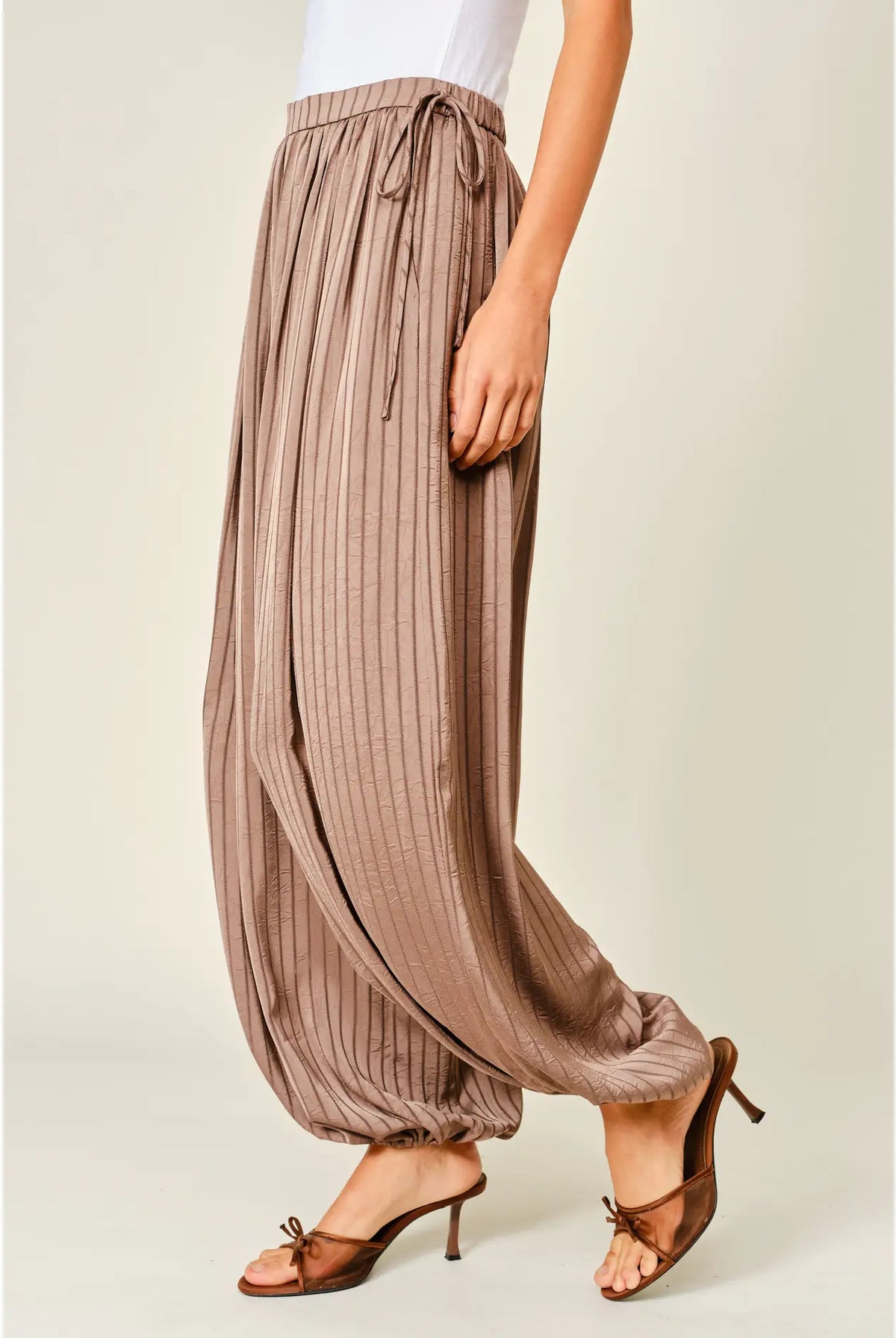 Zola Striped Satin Bubble Pants featuring a soft, glossy satin finish with a striped pattern, comfortable elastic waistband, adjustable drawstring side details, and functional side pockets. Designed with a relaxed, voluminous balloon silhouette and a flowy, lightweight feel for an effortlessly chic look.