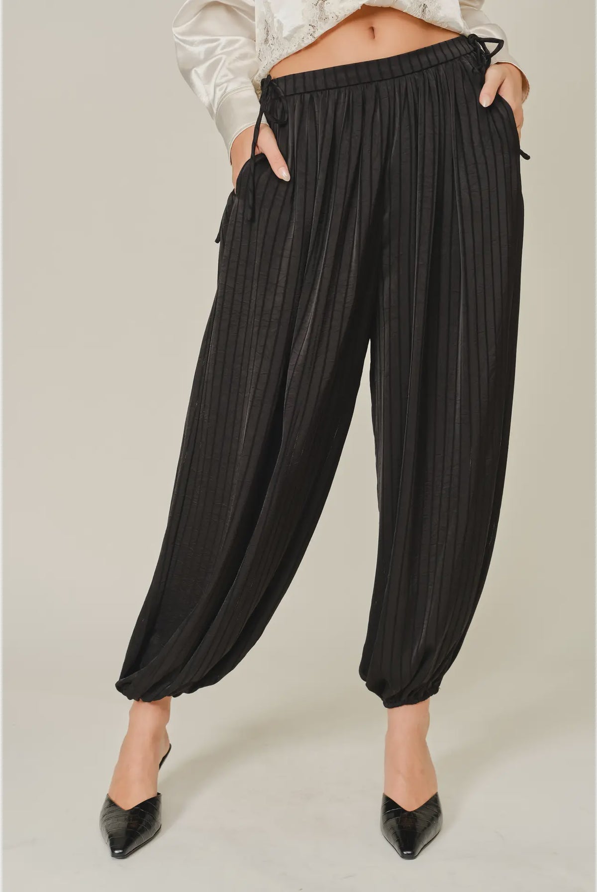 Zola Striped Satin Bubble Pants featuring a soft, glossy satin finish with a striped pattern, comfortable elastic waistband, adjustable drawstring side details, and functional side pockets. Designed with a relaxed, voluminous balloon silhouette and a flowy, lightweight feel for an effortlessly chic look.