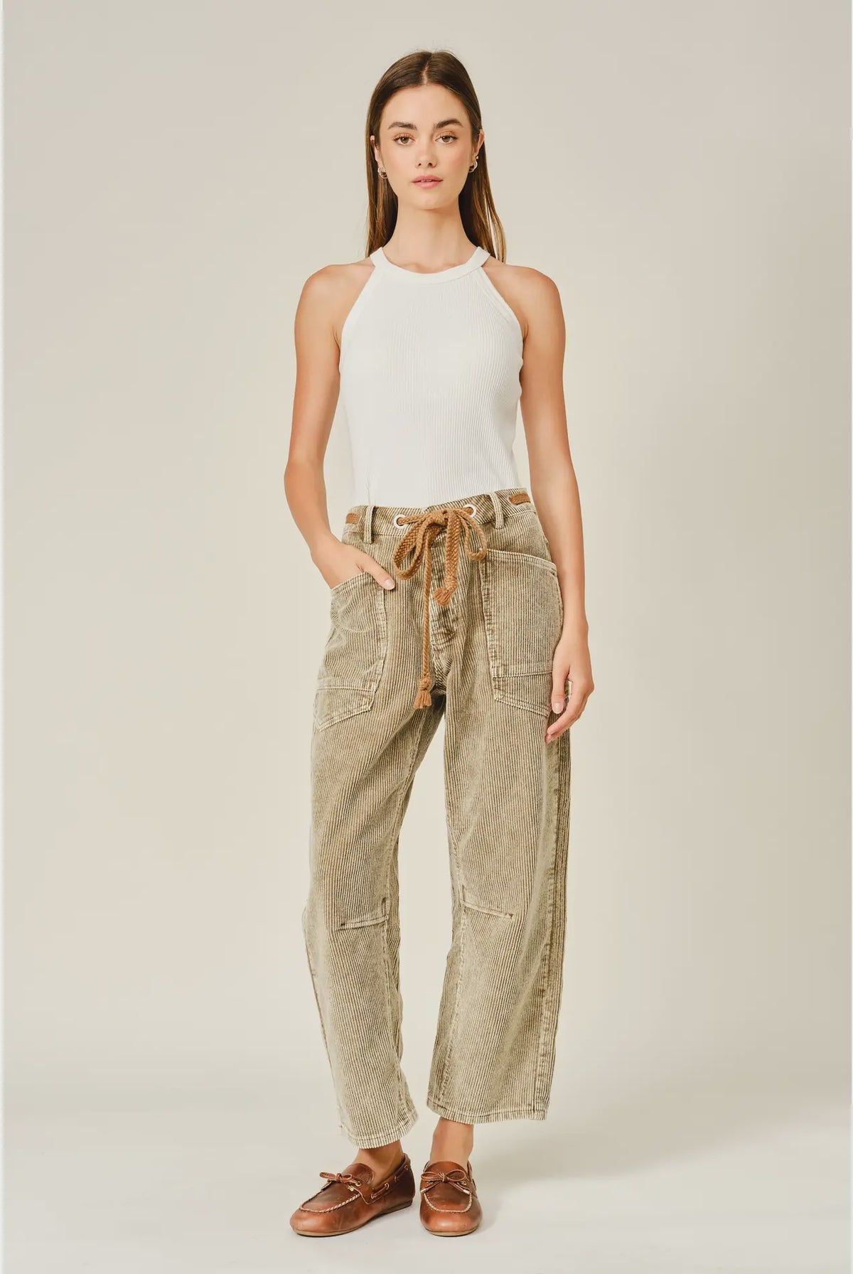 Women’s camel corduroy trousers featuring a subtle barrel fit, utility patch pockets, belt loops, and a rope tie waist.