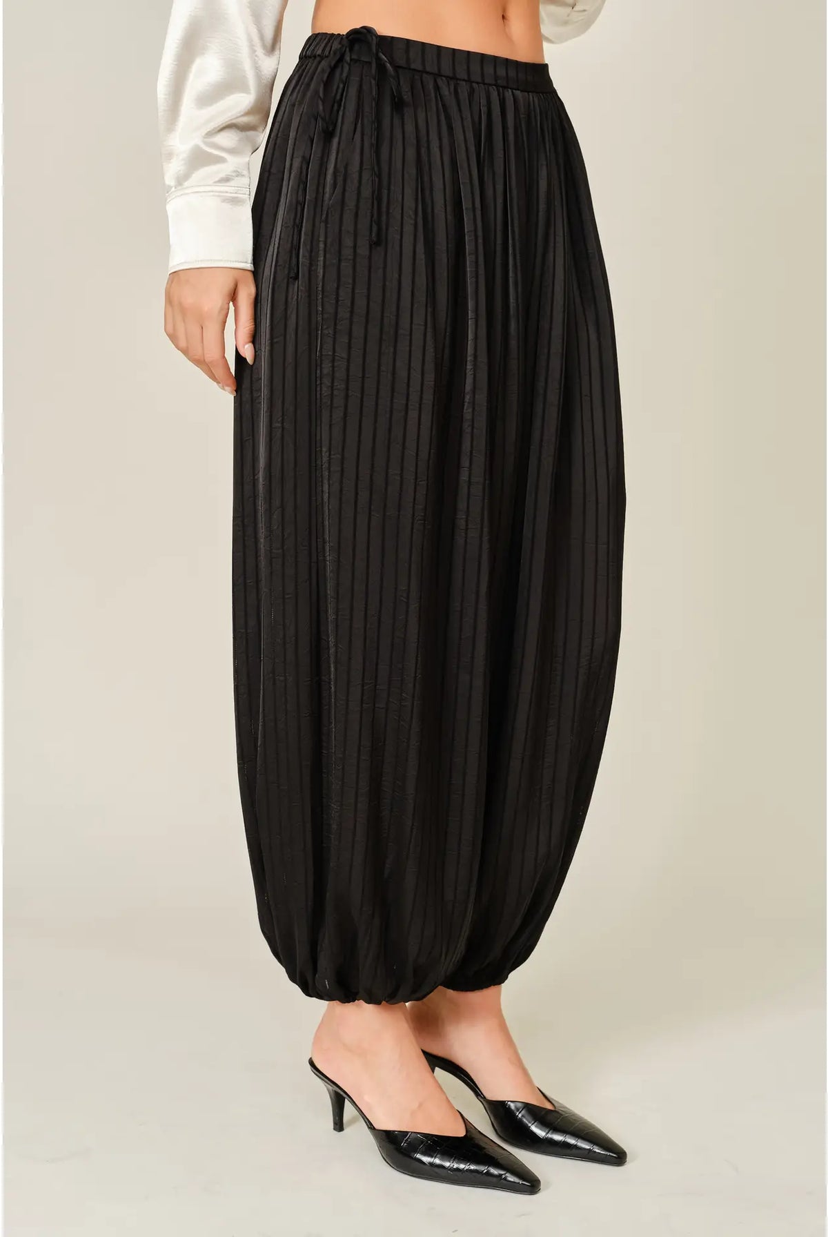 Zola Striped Satin Bubble Pants featuring a soft, glossy satin finish with a striped pattern, comfortable elastic waistband, adjustable drawstring side details, and functional side pockets. Designed with a relaxed, voluminous balloon silhouette and a flowy, lightweight feel for an effortlessly chic look.