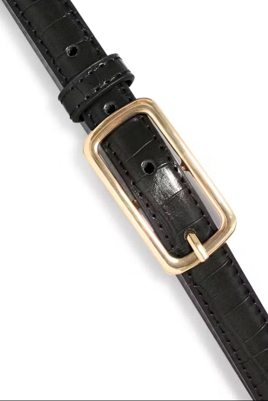 Black leather belt with a gold buckle on a white background