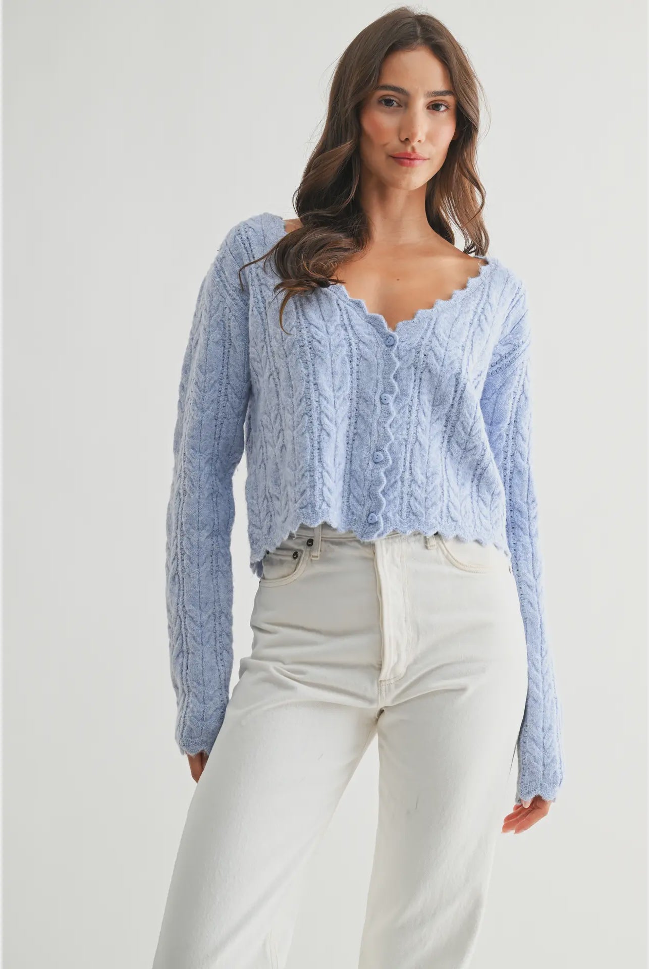 The Clara Cardigan in a soft pastel hue, featuring a cable-knit texture, scalloped hem and neckline, and button-front closure.