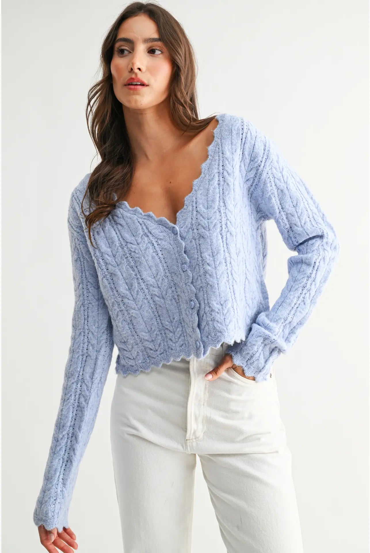 The Clara Cardigan in a soft pastel hue, featuring a cable-knit texture, scalloped hem and neckline, and button-front closure.