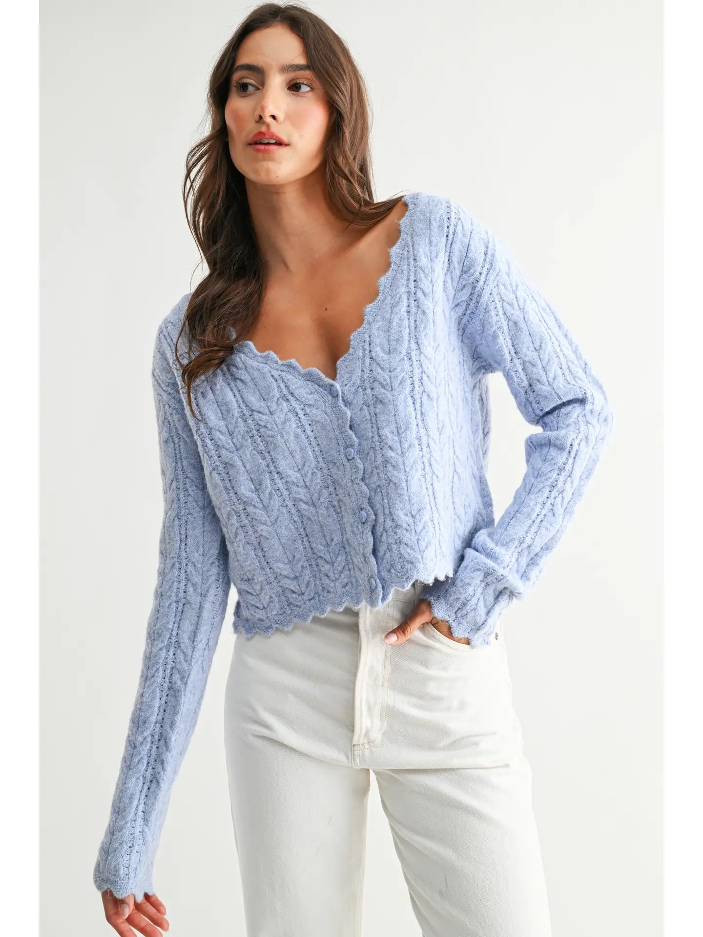 The Clara Cardigan in a soft pastel hue, featuring a cable-knit texture, scalloped hem and neckline, and button-front closure.