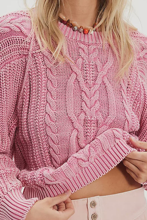 Woman wearing a pink knitted sweater and matching shorts on a white background