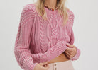 Woman wearing a pink knitted sweater and matching shorts on a white background