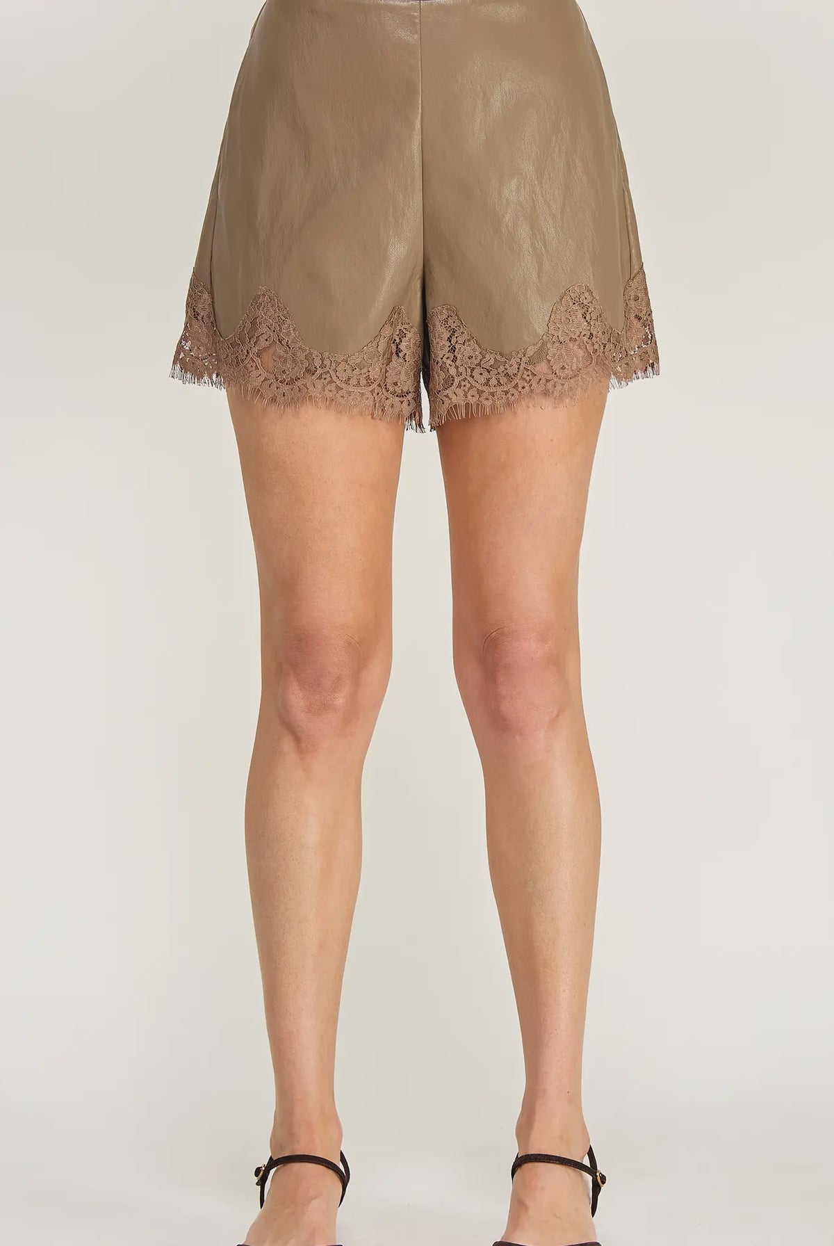 Clara Lace Trim Shorts featuring a smooth faux leather finish, flattering high-waisted silhouette, and delicate lace trim along the hem. Designed with a chic, feminine fit and edgy detailing. Pairs perfectly with the matching Clara Lace Trim Button-Down Top for a coordinated look.