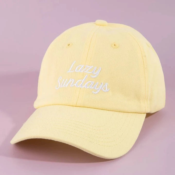 A pale yellow cotton baseball cap with 'Lazy Sundays' embroidered in white script on the front