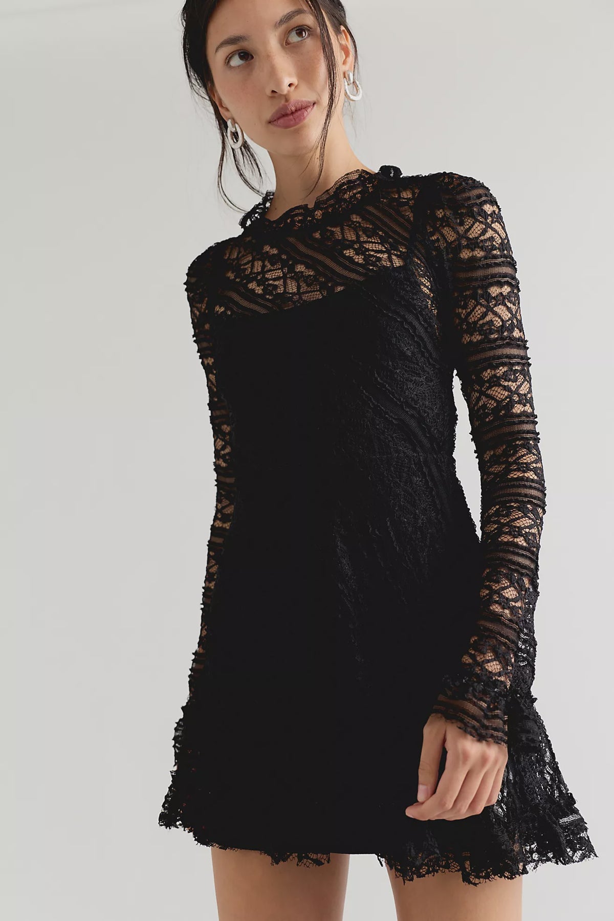 Romantic lace mini dress with an A-line silhouette, ruffled mock neckline, long sleeves, button-back closure, and removable slip lining.